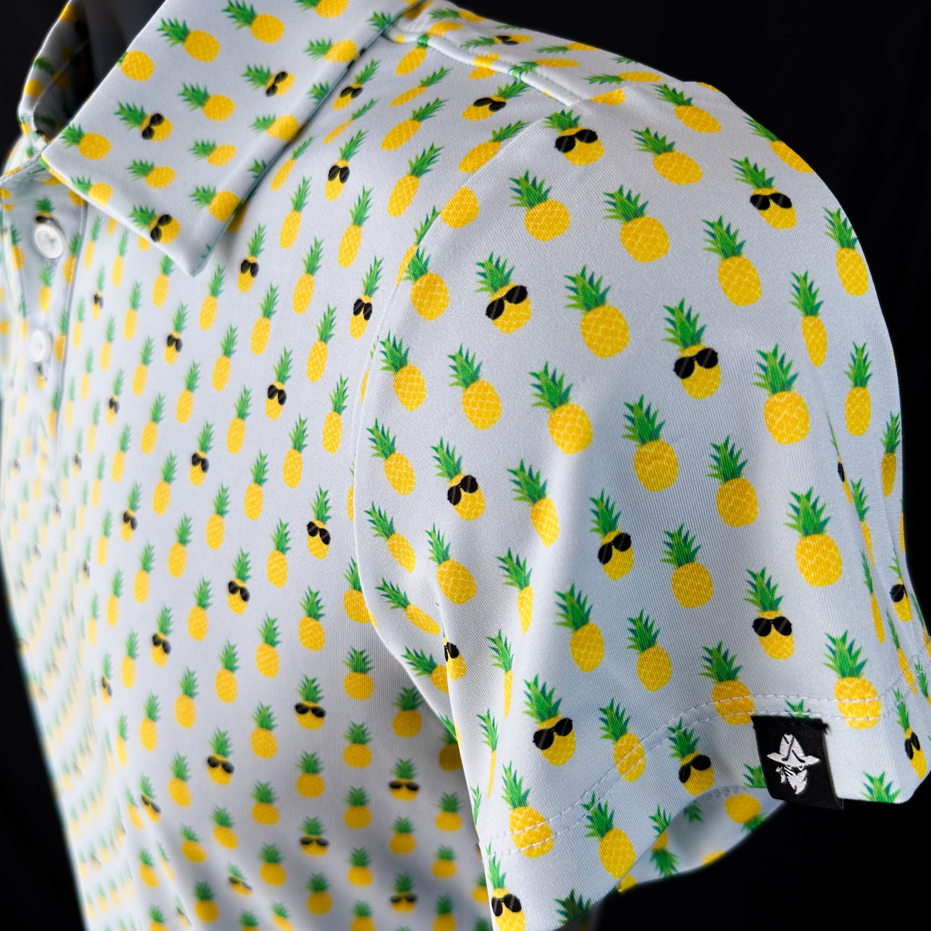 Side view of La Piña Girls Junior Golf Polo in light blue with playful pineapple print, showcasing moisture-wicking fabric, SPF 50 protection, wrinkle-resistance, and 4-way stretch. Perfect junior golf clothing for girls aged 8-14. Golf Bandit Junior Golf Polos are the best quality in US Kids Golf apparel.
