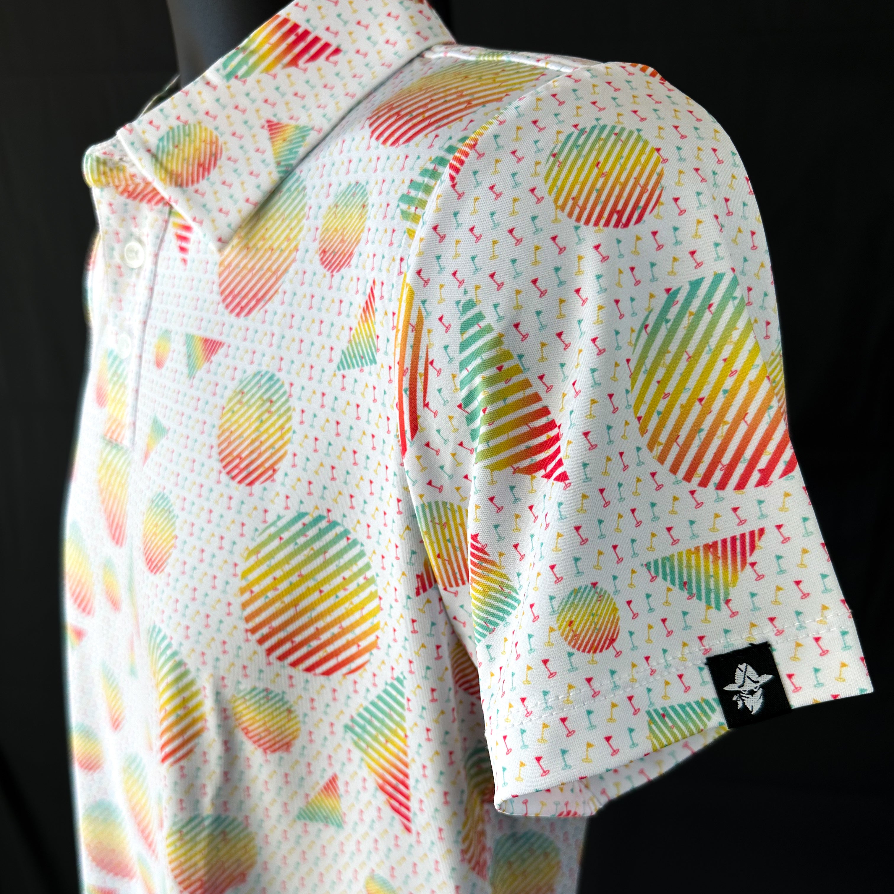Side view of Sharpshooter Boys Junior Golf Polo in a vibrant geometric design with mini golf flags, showcasing moisture-wicking fabric, SPF 50 protection, wrinkle-resistance, and 4-way stretch. Perfect junior golf clothing for boys aged 8-14. Golf Bandit Junior Golf Polos are the best quality in US Kids Golf apparel.