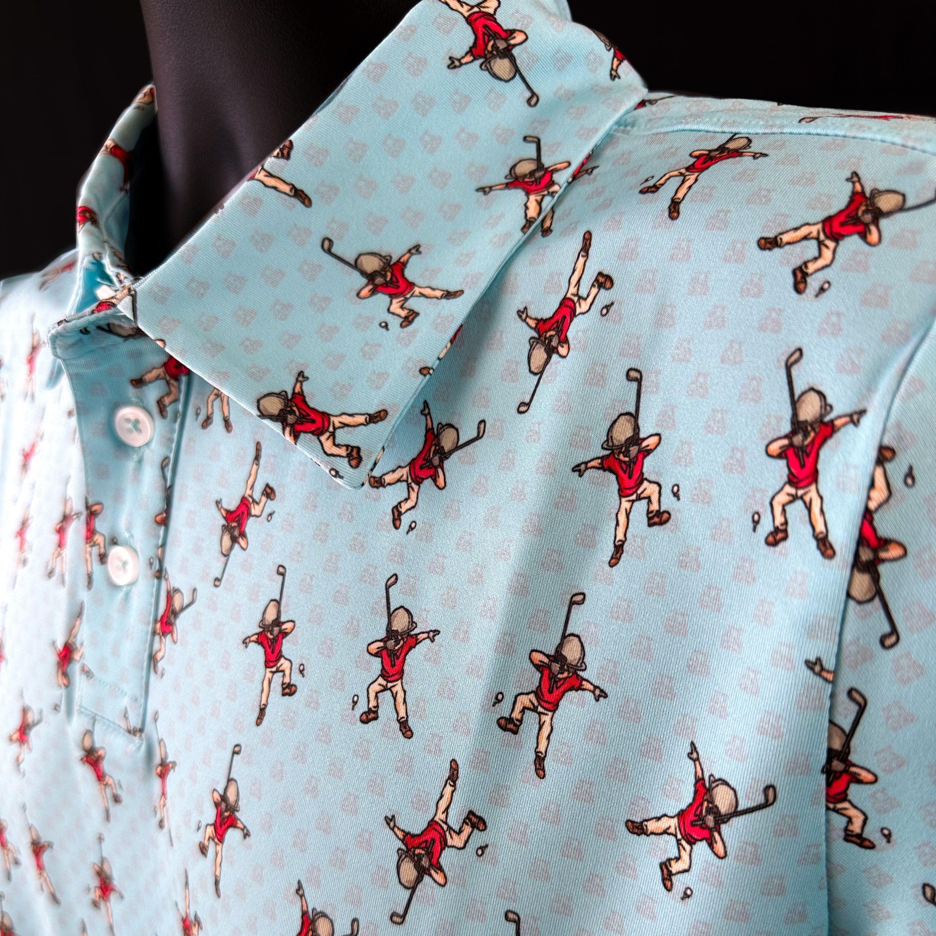 Close-up of Dapper Dab Boys Junior Golf Polo in light blue with playful dabbing golfer print, showcasing moisture-wicking fabric, SPF 50 protection, wrinkle-resistance, and 4-way stretch. Perfect junior golf clothing for boys aged 8-14. Golf Bandit Junior Golf Polos are the best quality in US Kids Golf apparel.